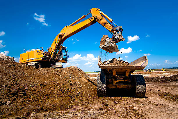 Industrial truck loader excavator moving earth and unloading int Industrial truck loader excavator moving earth and unloading into a dumper truck mining equipment stock pictures, royalty-free photos & images