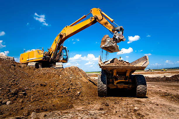 Industrial truck loader excavator moving earth and unloading int Industrial truck loader excavator moving earth and unloading into a dumper truck shovel in sand stock pictures, royalty-free photos & images