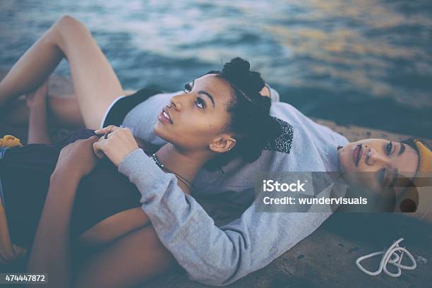 Teen Grunge Girl Friends Lying Together Alongside Water Stock Photo - Download Image Now