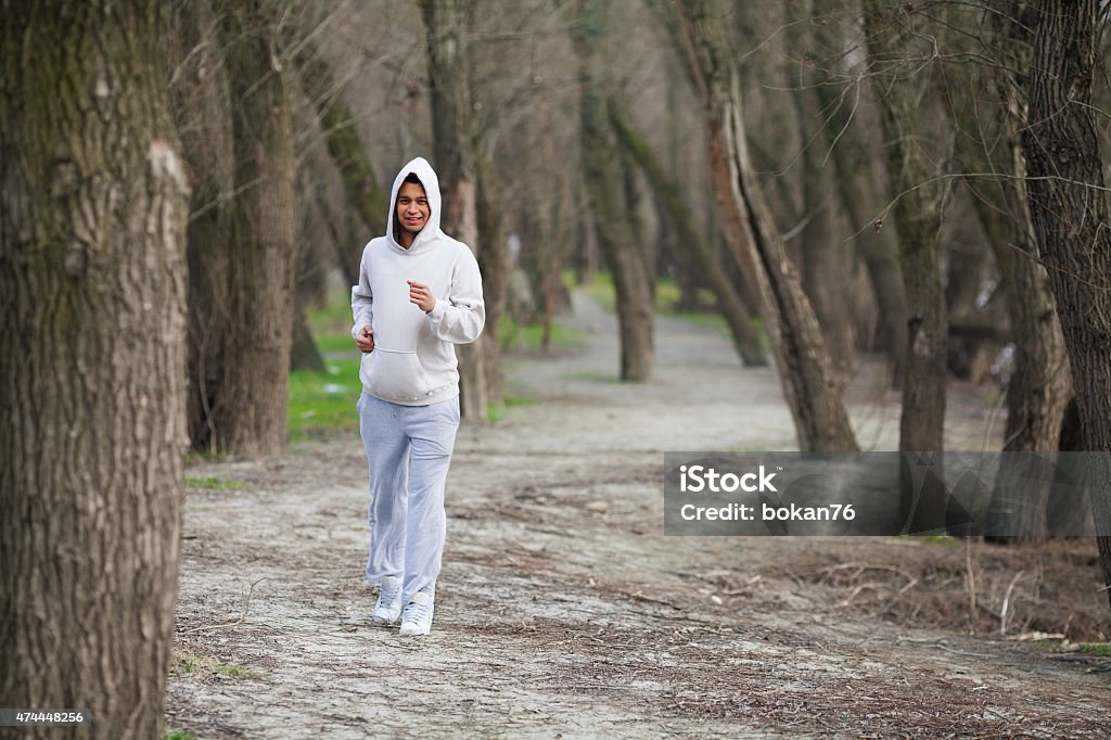 Young Man Running in a Park Cheerful young man jogging in nature 20-24 Years Stock Photo