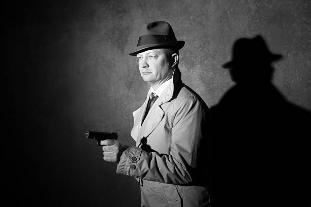 male detective with a gun in 40s film noir style Black and white image of a male detective with a gun and fedora. Image created in film noir style. gangster photos stock pictures, royalty-free photos & images