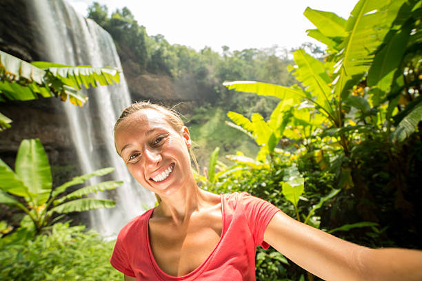 istock Young woman taking selfie with waterfall on background 474451258
