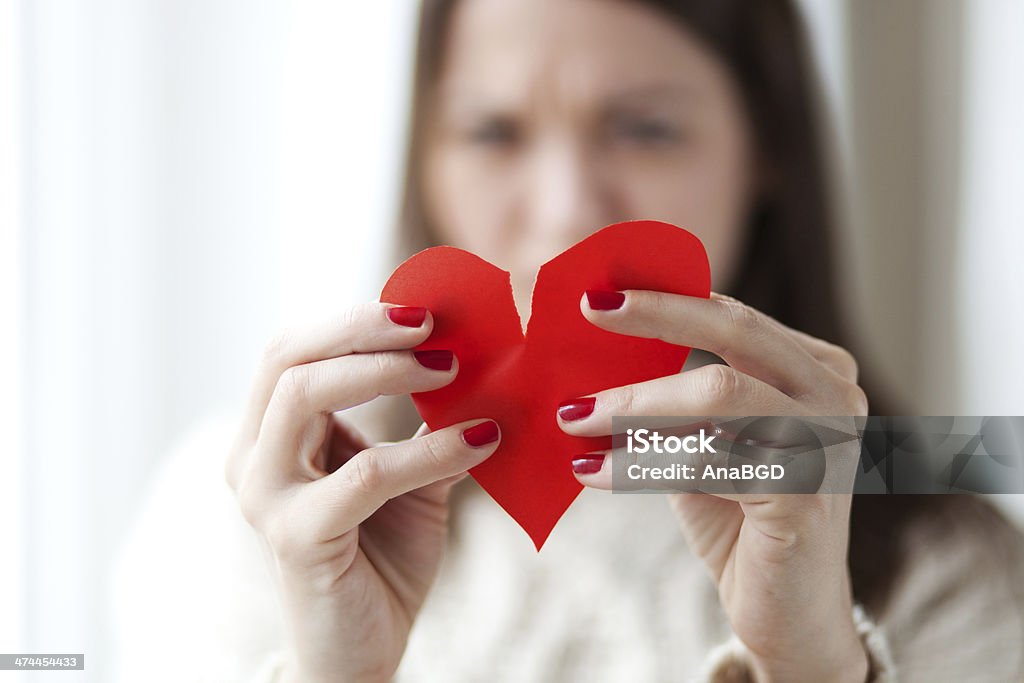 Heart broken Image of woman tearing paper heart apart, shallow depth of field Adult Stock Photo