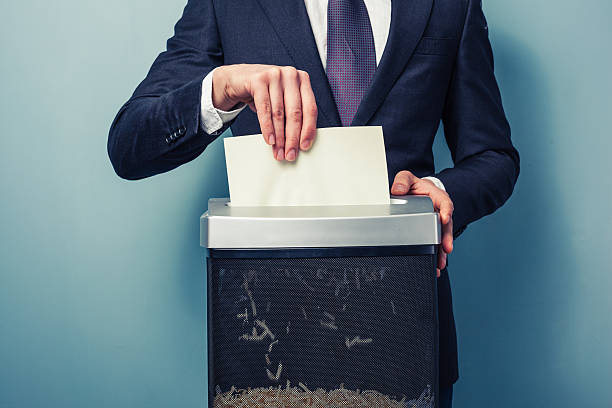 Businessman shredding documents A Businessman is shredding important documents paper shredder stock pictures, royalty-free photos & images