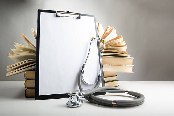 istock Open hardback books on the table, blank medical clipboard with 474456562
