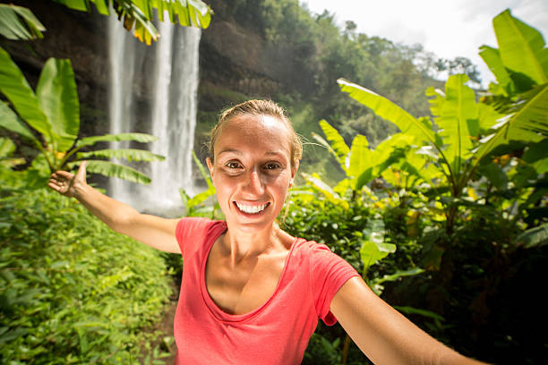 istock Girl in jungle taking selfie with waterfall 474459172