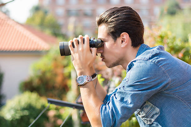 joven mirando a través de la búsqueda de fuera binocular - binoculars watching optical instrument closed fotografías e imágenes de stock