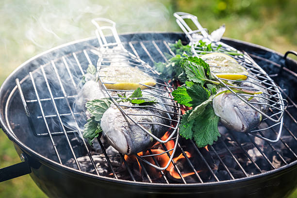 grillades de poisson frais, de citron et de plantes aromatiques - broiled fish photos et images de collection