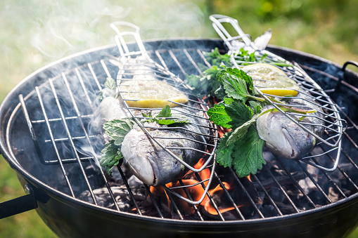 Grilling fresh fish with lemon and herbs.
