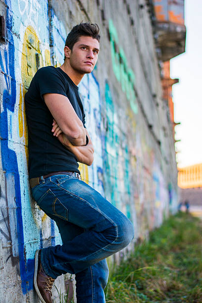 istock Attractive young man standing against colorful graffiti wall 474461640