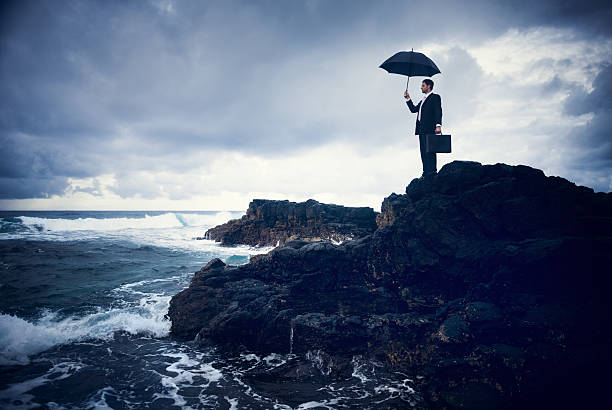 uomo d'affari in pioggia oceano - storm sea business uncertainty foto e immagini stock