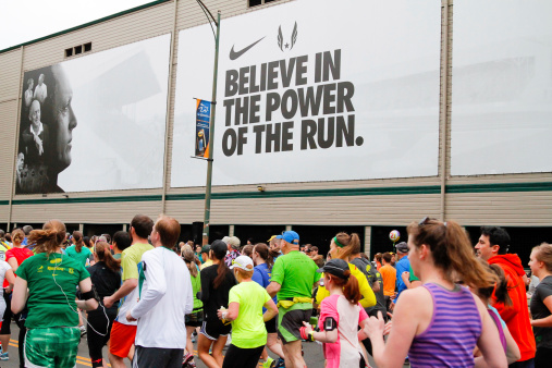 Eugene, OR, USA - April 28, 2013: 2013 Eugene Marathon start with runners next to Historic Hayward Field at the University of Oregon with a Nike advertisement in the background.