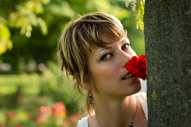 atrakcyjna młoda kobieta w ogrodzie lub parku z czerwona róża - human hair women horizontal rose petals zdjęcia i obrazy z banku zdjęć