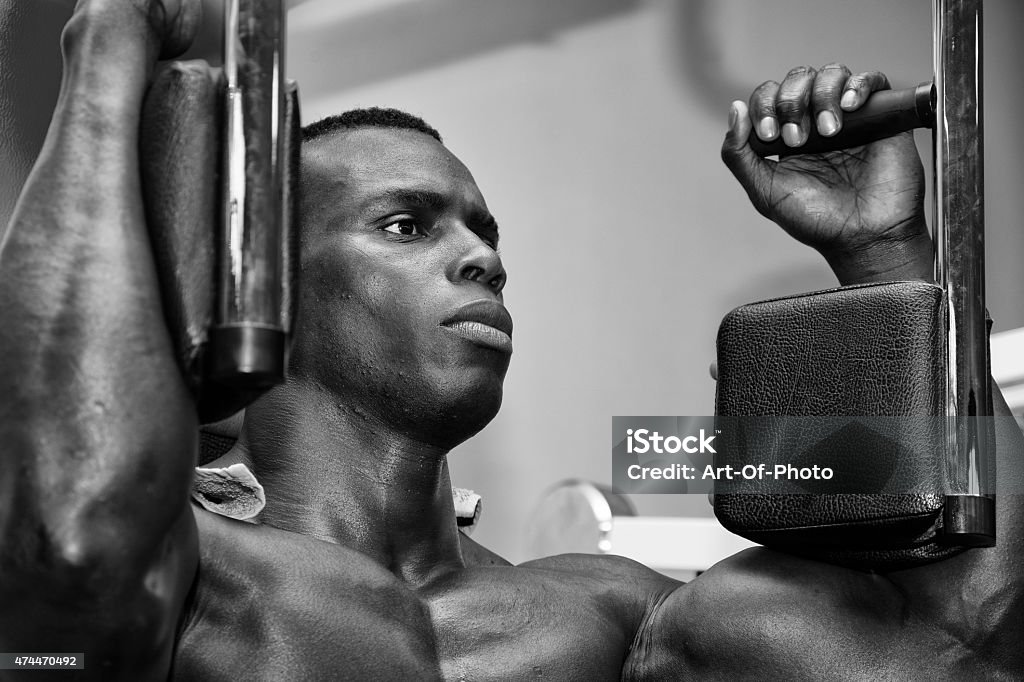 Hunky muscular black bodybuilder working out in gym Hunky muscular black bodybuilder working out in gym, exercising pecs on machine 2015 Stock Photo