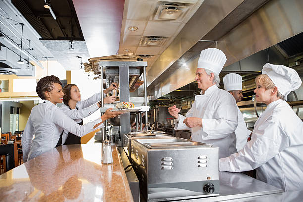 istock Chefs and waitstaff working together in busy restaurant kitchen 474471547
