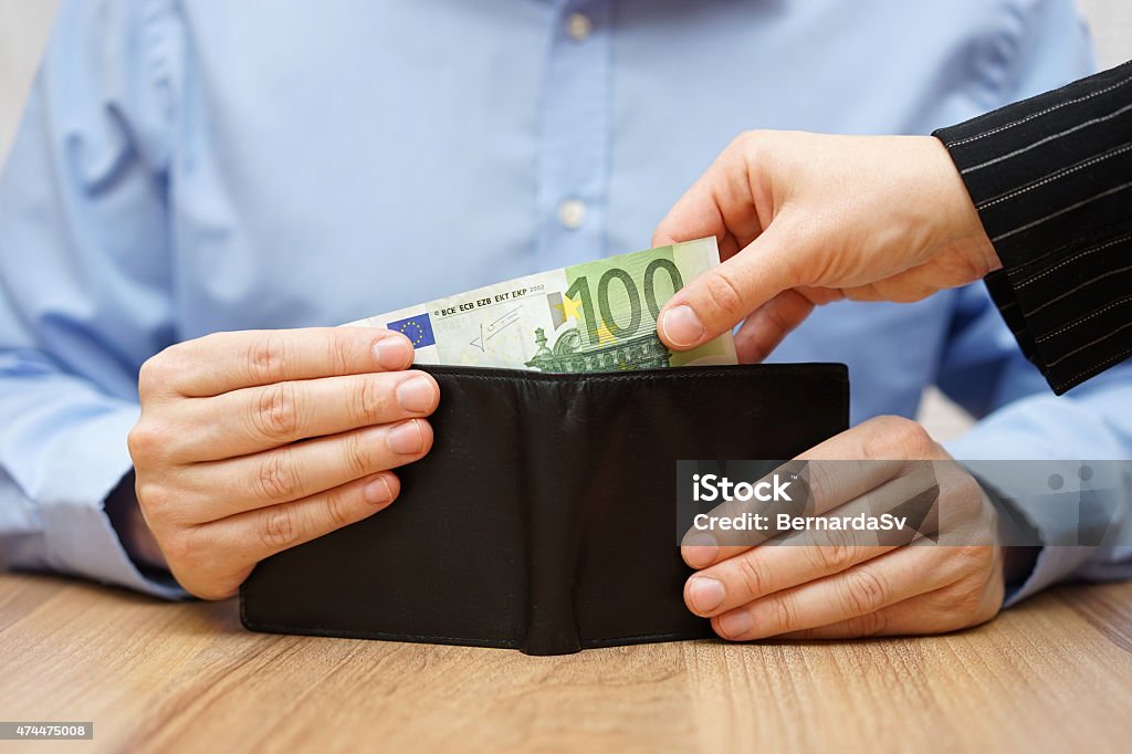 Woman is taking money out of a husband's wallet Currency Stock Photo