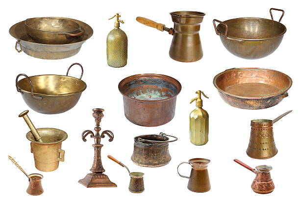 Grouping of copper pots on a wood plank surface photographed against a distress board in a still life setting with selective focus.