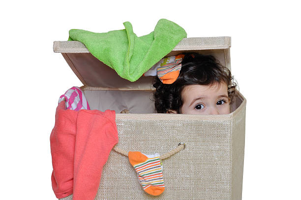 Little girl hiding in laundry basket stock photo