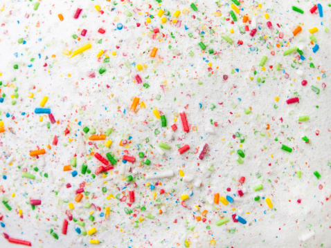 Sugar sprinkles on wooden spoon over white table in the kitchen at home.