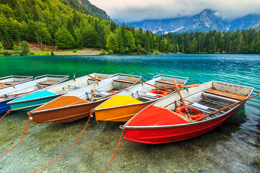 Colorful boats on the crystal clear alpine lake,near Slovenian-Italy border,Lake Fusine,Italy,Europe