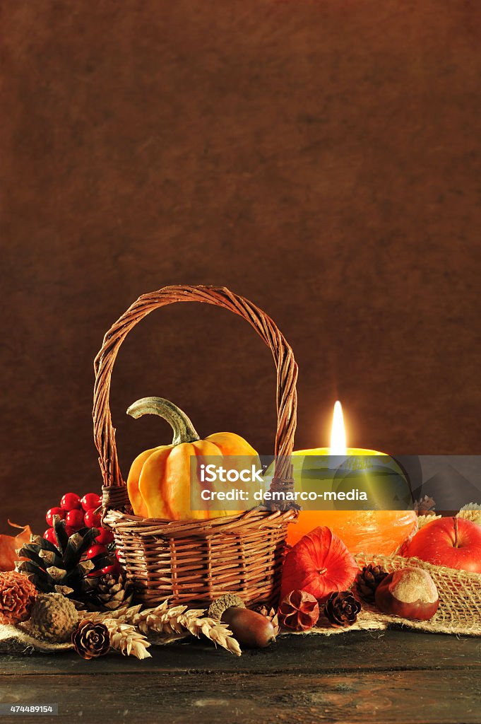 Thanksgiving small pumpkin in basket on old weathered wooden floor in candlelight 2015 Stock Photo