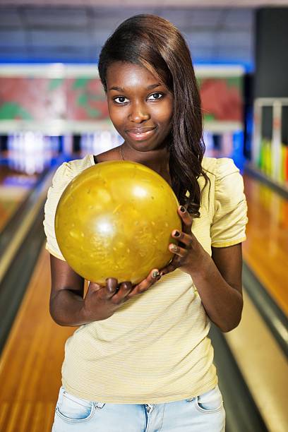 Strike. Ten bowling pins and bowling ball isolated on the yellow background. White skittles with red stripes.