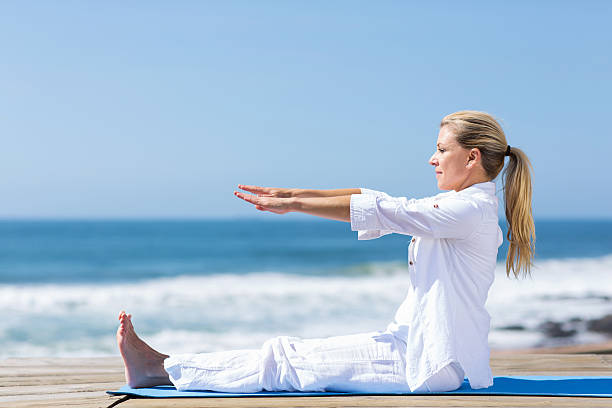 istock senior woman stretching on beach 474489495