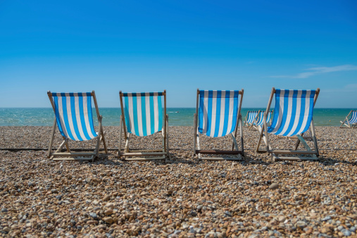 4 blue deck chairs on a pebble beach