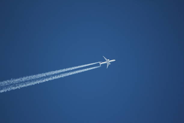 istock Aircraft with white condensation trail in the clear blue sky 474492619