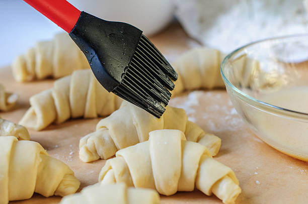 istock Croissants cooking and brushing with egg on table with flour 474492844