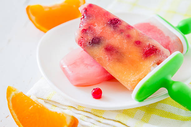 istock Fruit ice pops on white plate, orange slices, plaid napkin 474493810