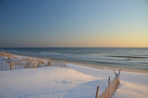 Snow covered beach and dunes at sunrise in New Jersey.