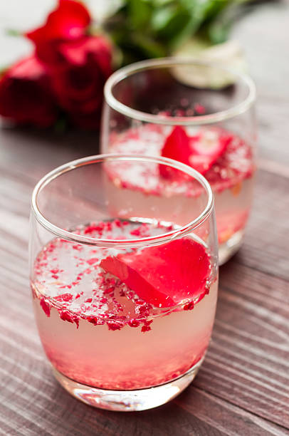 istock Pink Cocktail with fresh rose petals on wooden table 474497892