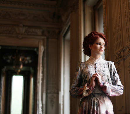 Young beautiful woman standing in the palace room. 
