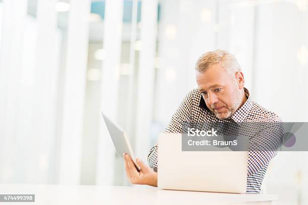 Multitasking Businessman Using Wireless Technology In The Office Stock Photo - Download Image Now