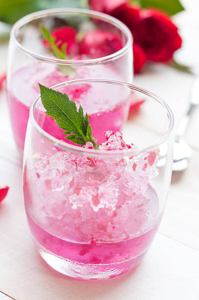 istock Pink Cocktail with fresh rose petals on wooden table 474499568