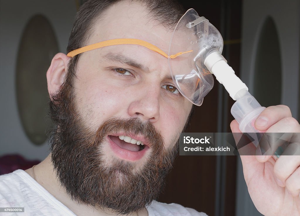 bearded man with an asthma inhaler to breathe health 2015 Stock Photo