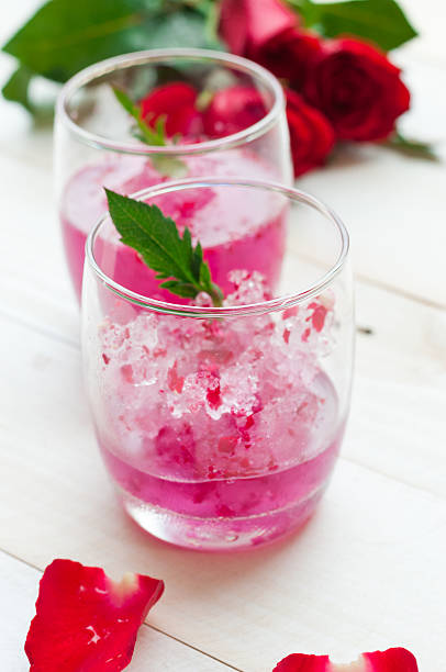 istock Pink Cocktail with fresh rose petals on wooden table 474500400