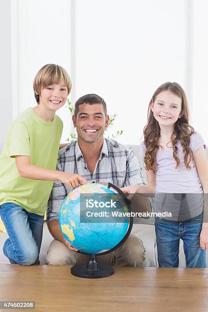 Father With Son And Daughter Exploring Map On Globe Stock Photo - Download Image Now