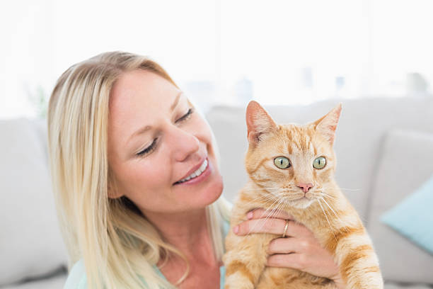 istock Young woman holding cat at home 474502354