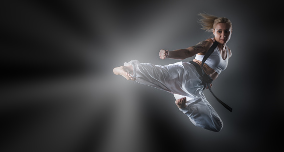 Woman practicing karate at dark background,