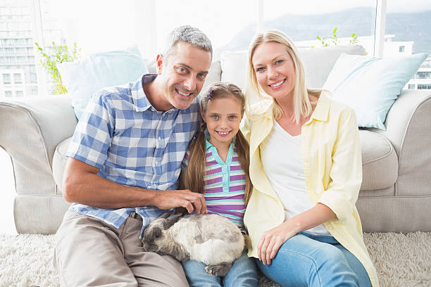 istock Happy parents and daughter with rabbit in living room 474506708