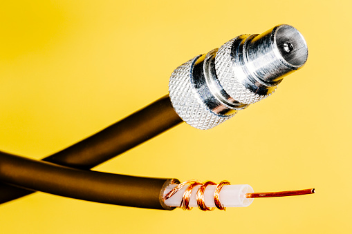 Co-axial plug with brown cable against a yellow background. AdobeRGB colorspace.