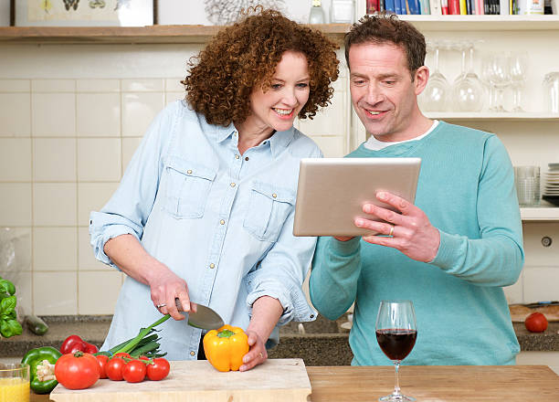 Happy man and woman looking at tablet in the kitchen