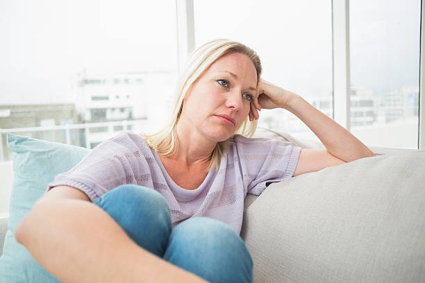 istock Sad woman sitting on sofa 474511482