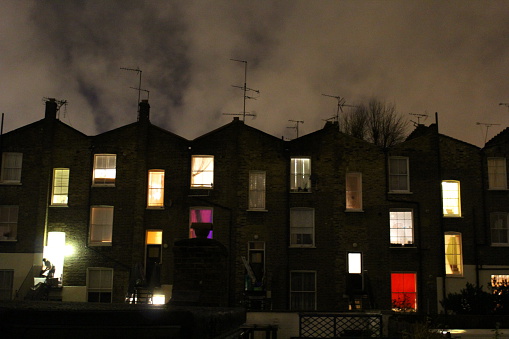 A row of terrace houses shine brightly by night.