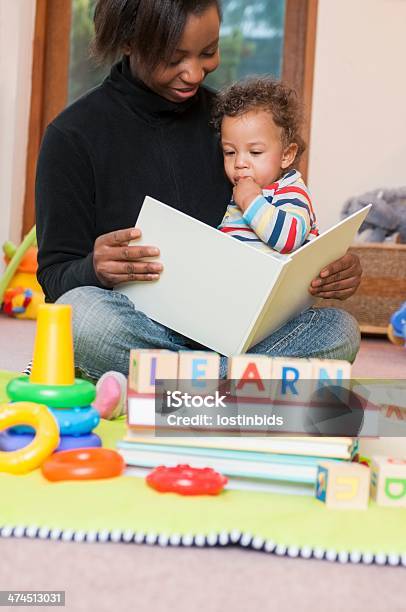 Portrait Of Carer Reading Book To Baby Stock Photo - Download Image Now - Baby - Human Age, 6-11 Months, Adult