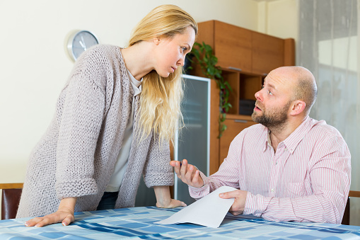 Young unpleased couple having conflict over financial documents at home