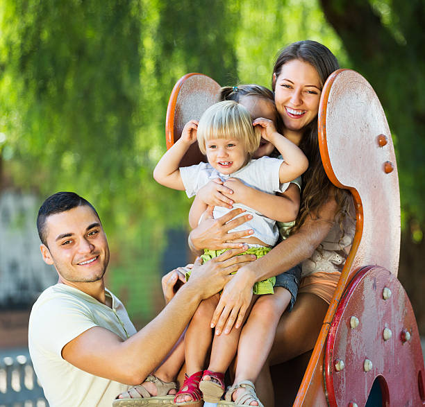 istock Smiling parents helping kids on slide 474521174