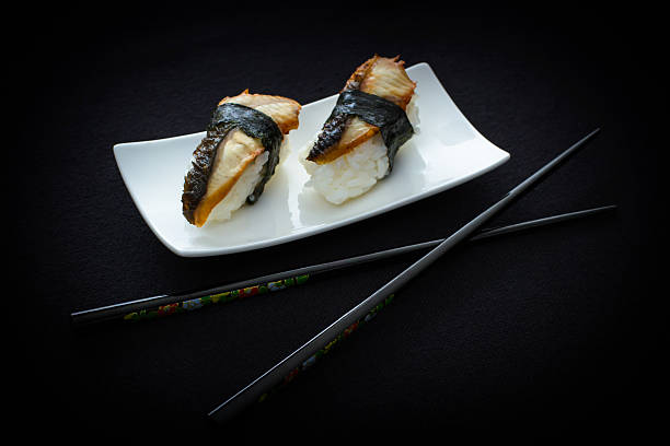 istock Two nigiri eel sushi with chopstick on black 474537782